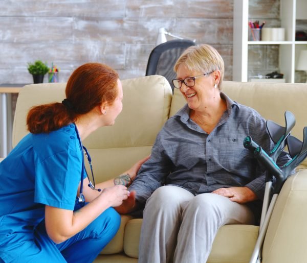 Female nurse talking with old woman with alzheimer in nursing home